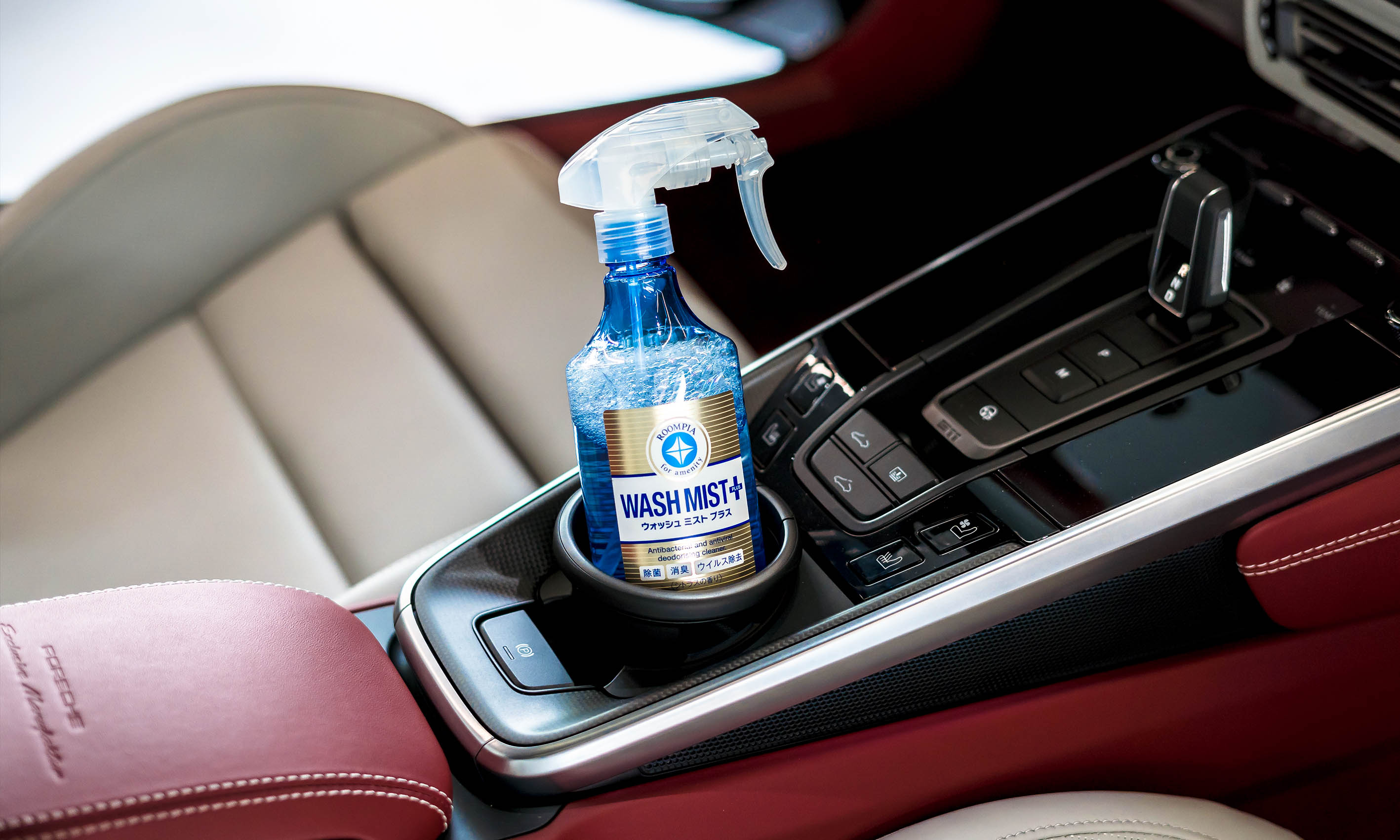 A photo of a Soft99 car care product Wash Mist Plus placed in the car's cup holder.