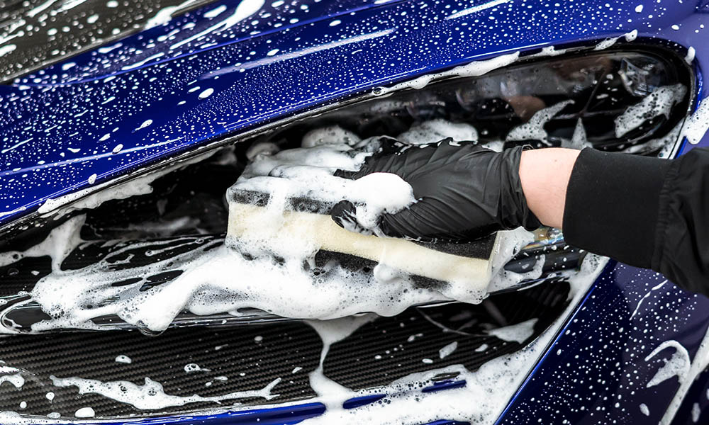 Photo of person using a Soft99 QJUTSU Ultrasoft Sponge to hand wash the car.