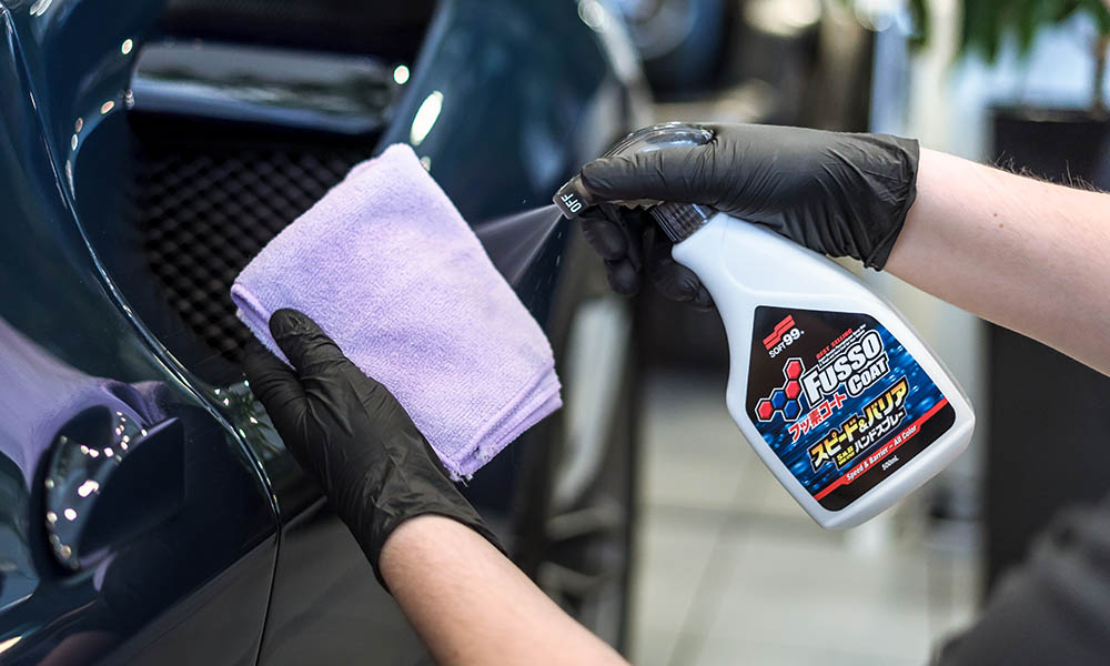 Photo of a Soft99 car care product Fusso Coat Speed & Barrier being sprayed onto a microfibre cloth, a process usually done before applying the product to the paintwork.