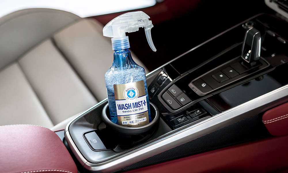 Photo of a Soft99 car care product Wash Mist Plus, inside a drink holder in a car's interior.